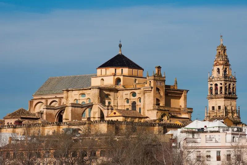 La Mezquita-Catedral de Córdoba, con su cúpula y el crucero renacentista, y la torre campanario a la derecha, bajo un cielo azul.